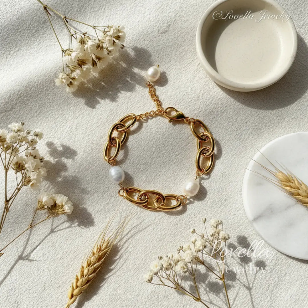 Gold bracelet with pearls on a light surface with dried flowers and a small dish.