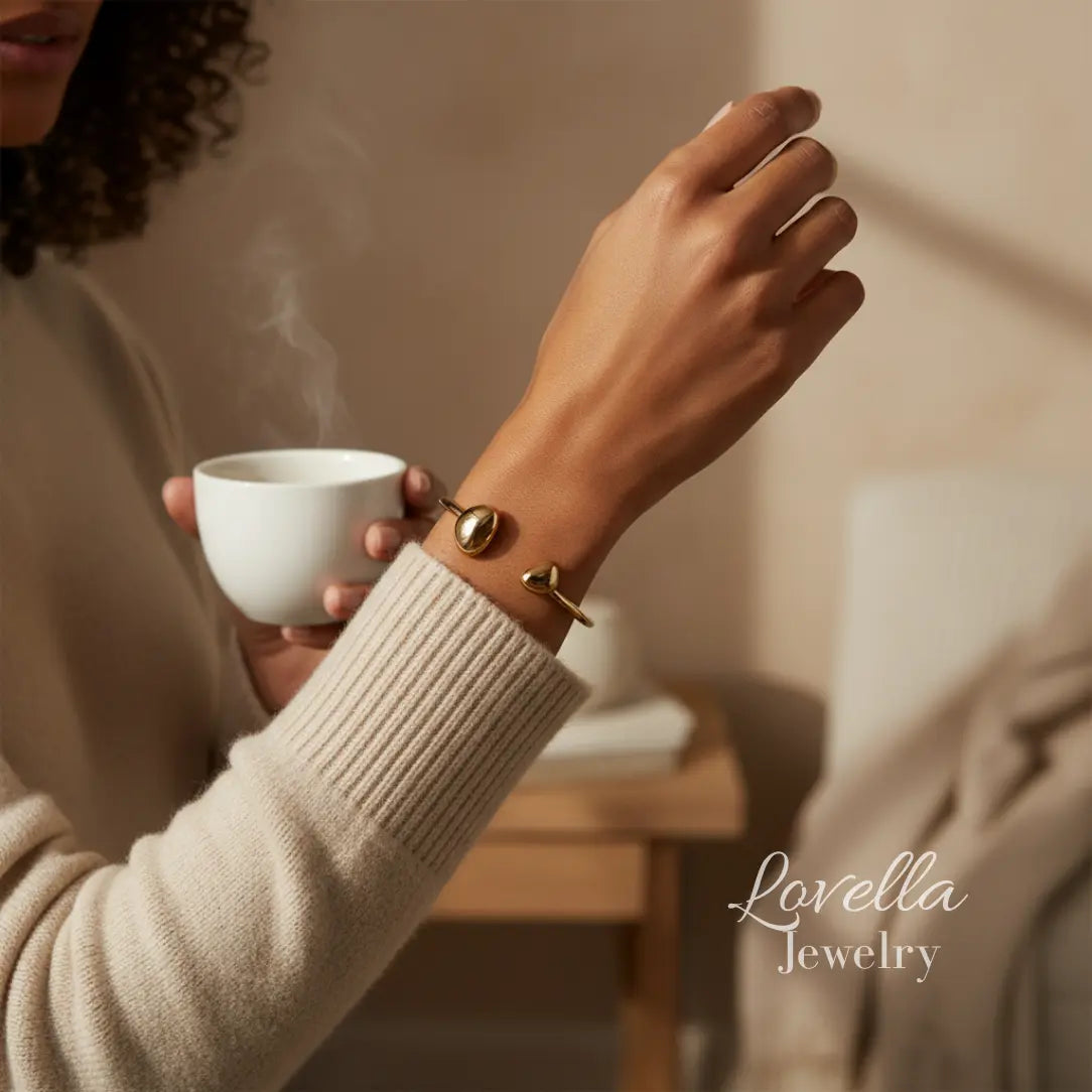 Person holding a steaming cup with Lovella Jewelry visible