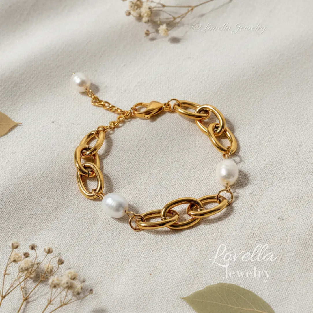 Gold chain bracelet with pearls on a light fabric background