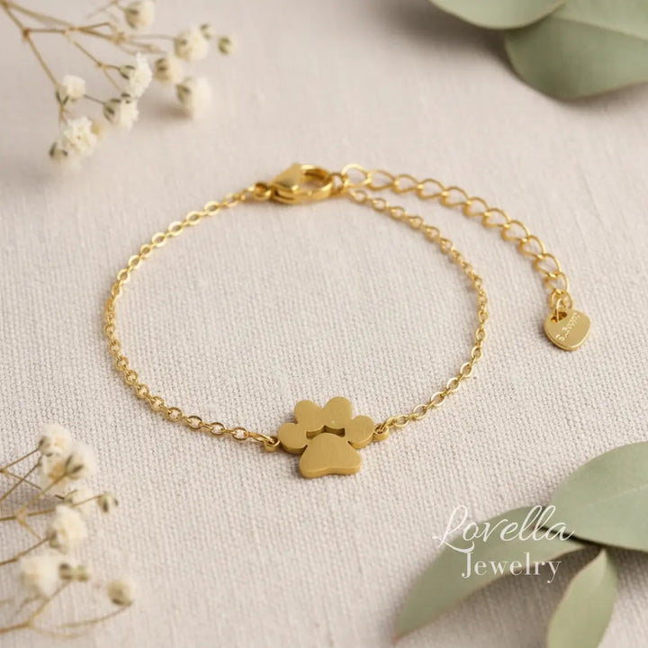 Gold bracelet with heart-shaped charms on a light background with flowers and leaves.