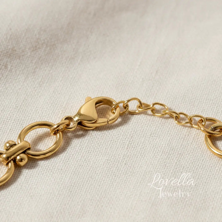 Gold bracelet on a light fabric background with 'Lorella Jewelry' branding.