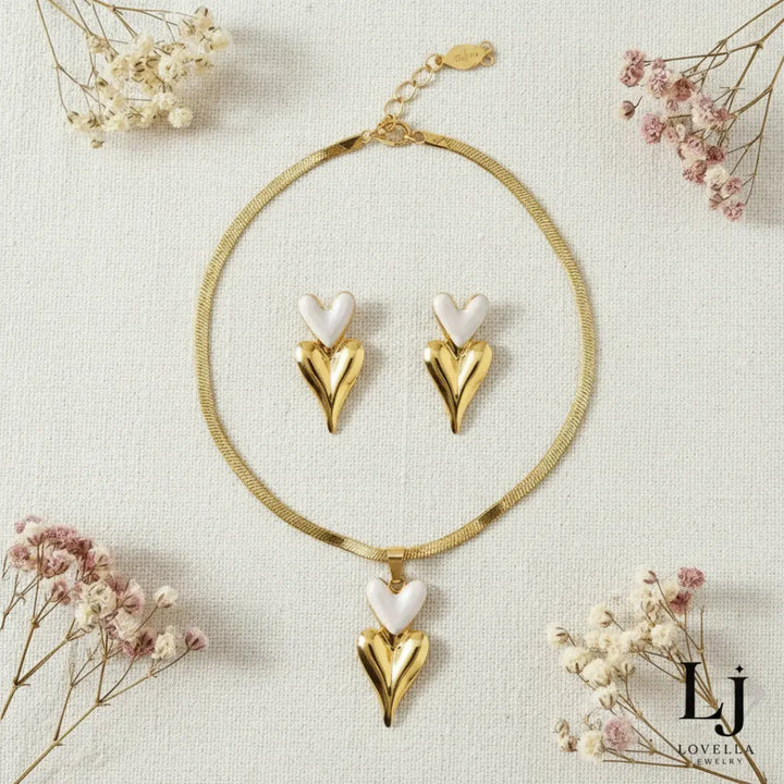 Heart-shaped gold and white jewelry set with dried flowers on a light background