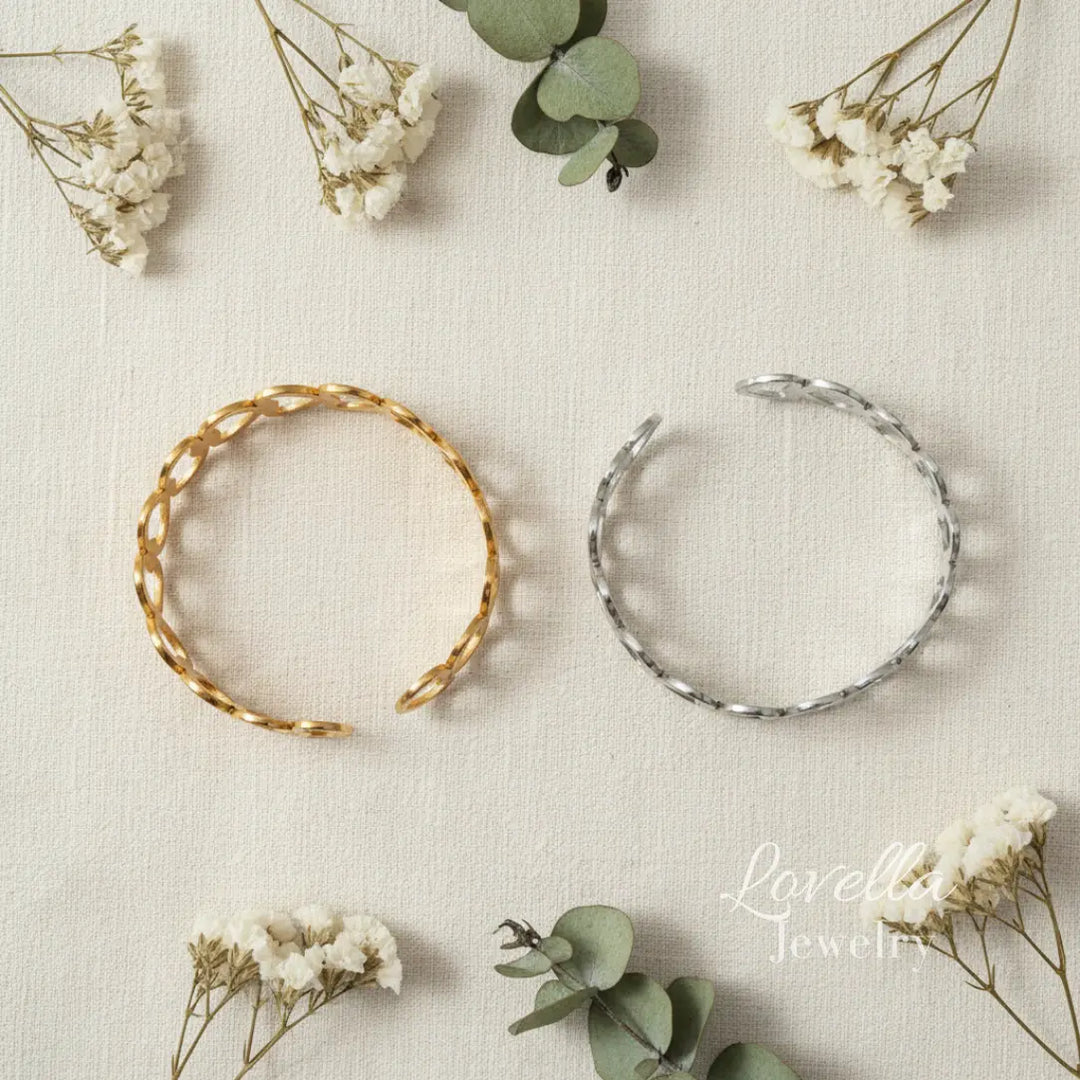 Two gold and silver hoop earrings on a textured surface with flowers and leaves.