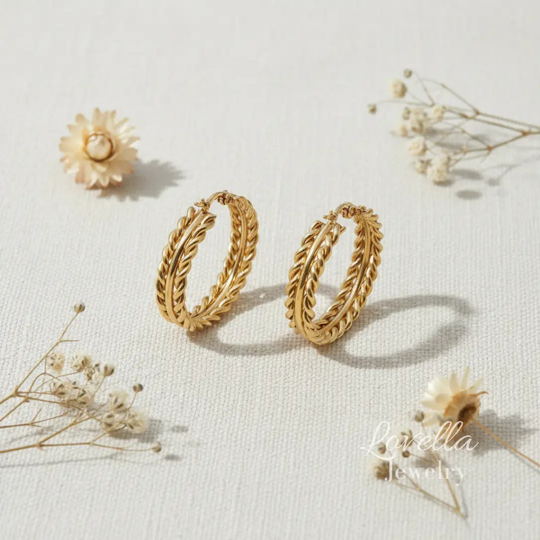 Gold hoop earrings on a light background with dried flowers.