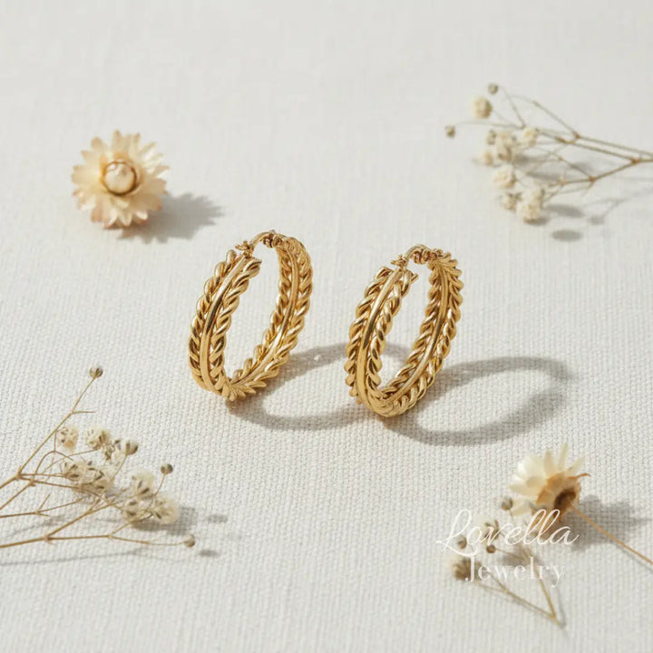 Gold hoop earrings on a light background with dried flowers.
