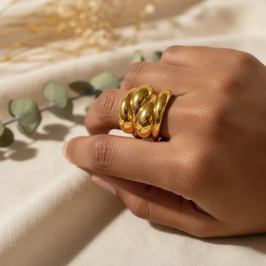 Hand wearing a gold ring with a soft background