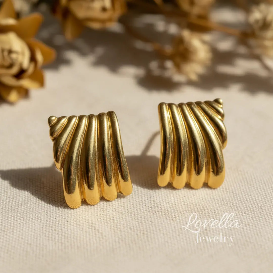 Pair of gold ribbed earrings on a light background with 'Lovella Jewelry' branding.