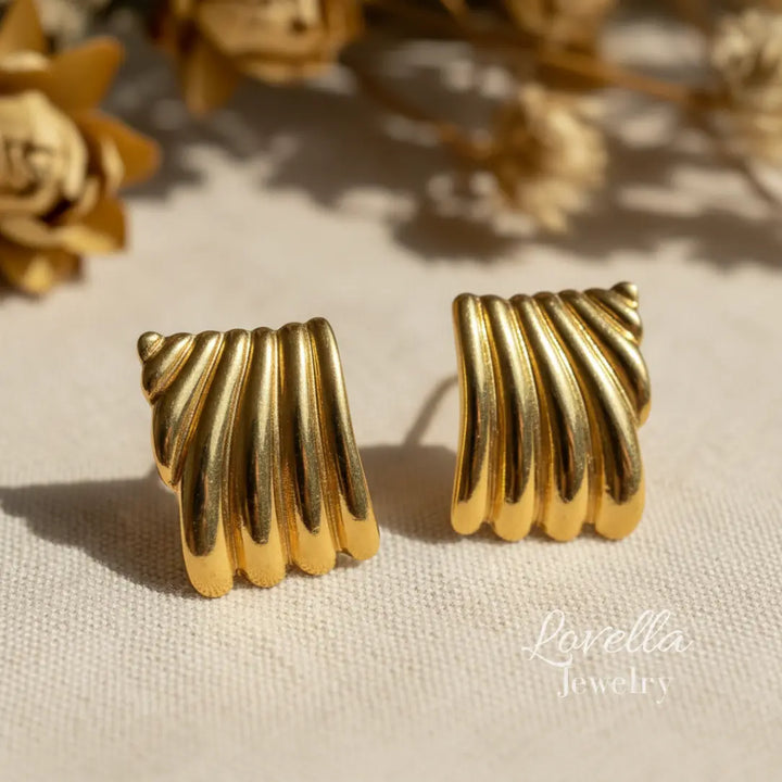Pair of gold ribbed earrings on a light background with 'Lovella Jewelry' branding.