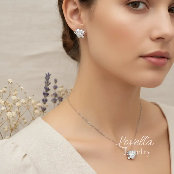 Woman wearing a necklace with a floral design, set against a neutral background with dried flowers.