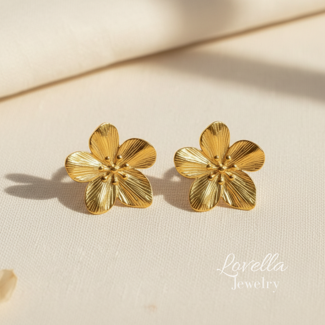 Gold flower-shaped earrings on a beige background with 'Lovella Jewelry' branding.