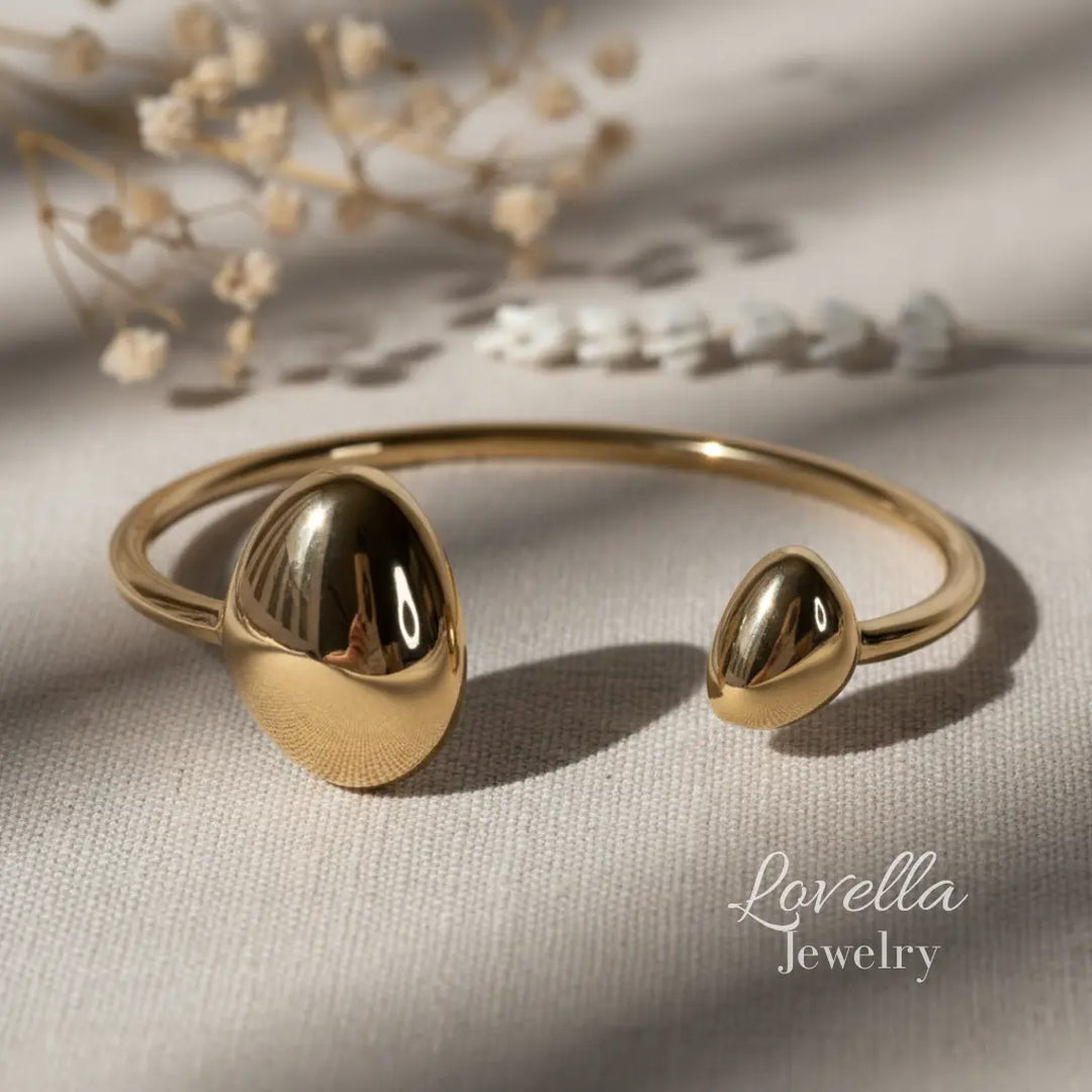 Gold bracelet with spherical ends on a neutral background, featuring Lovella Jewelry branding.
