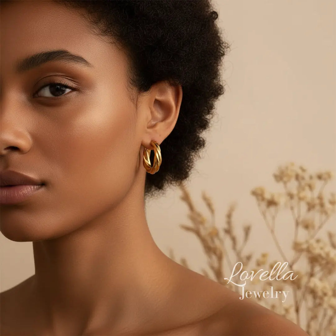 Close-up of a woman wearing gold hoop earrings with a neutral background and 'Lovella Jewelry' branding.