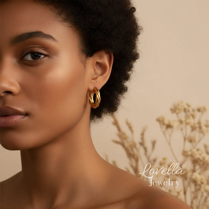 Close-up of a woman wearing gold hoop earrings with a neutral background and 'Lovella Jewelry' branding.