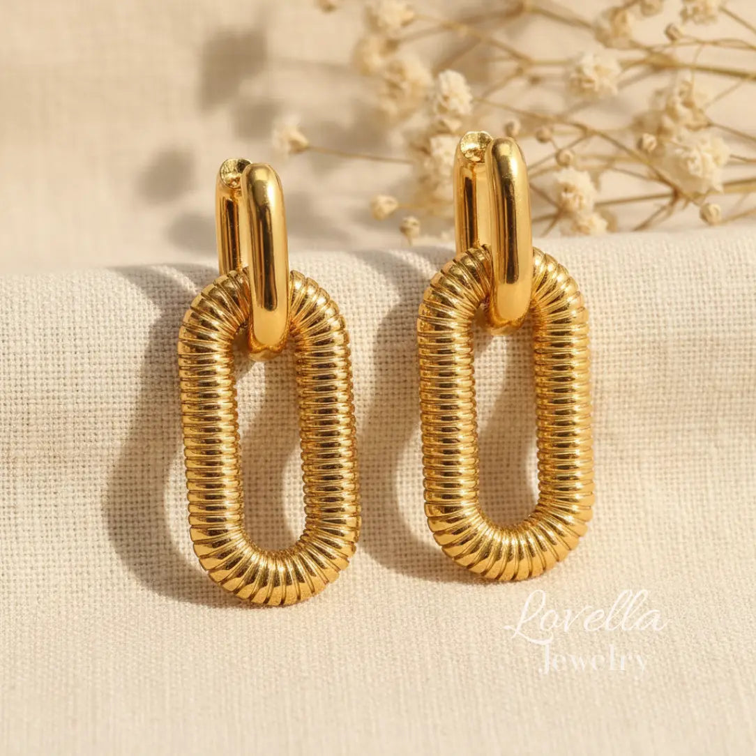 Gold hoop earrings on a beige fabric background with ‘Lovella' branding.