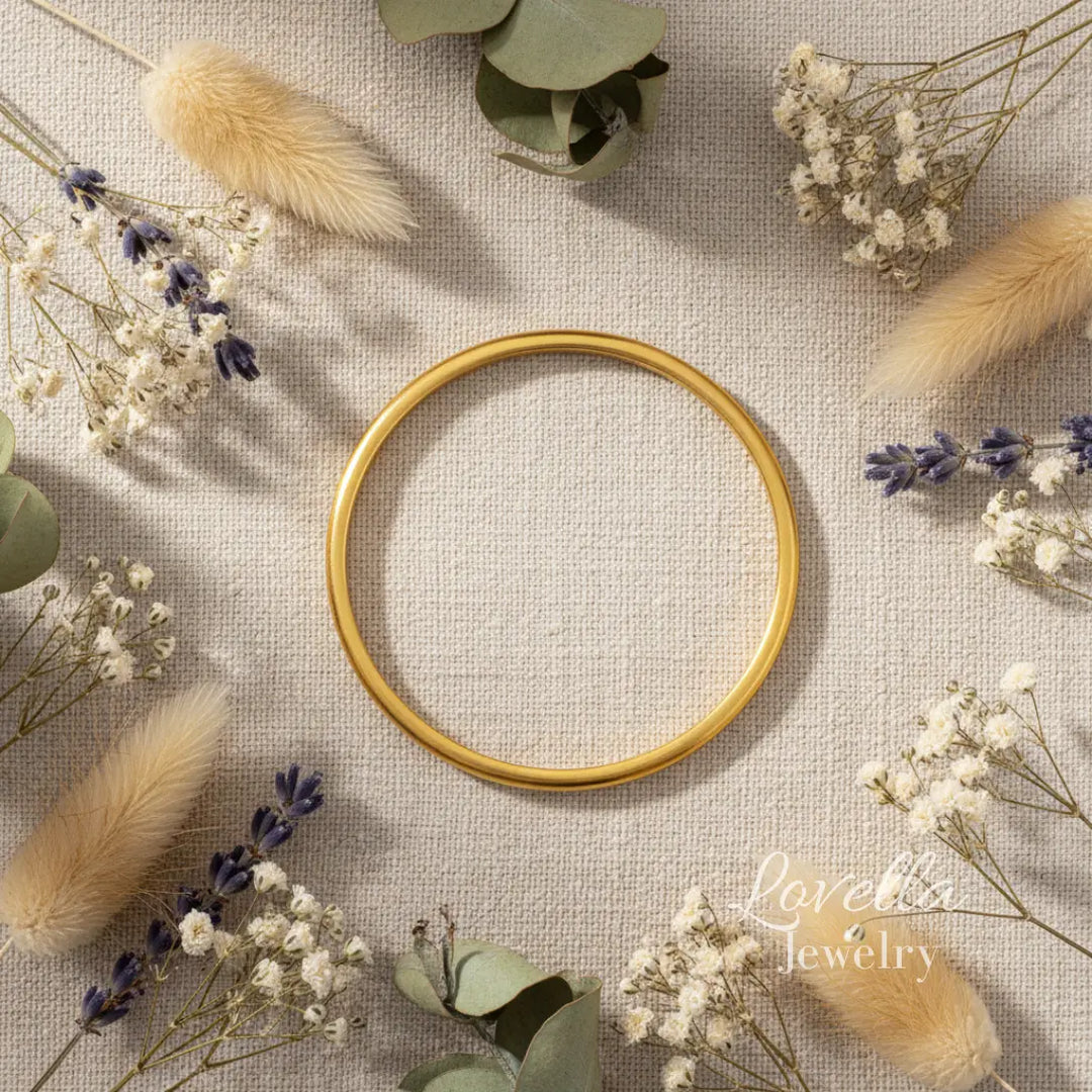 Gold bangle on a textured surface with dried flowers and leaves