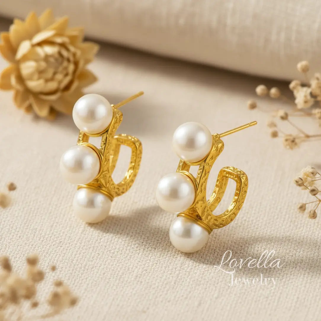 Gold earrings with pearls on a beige fabric background