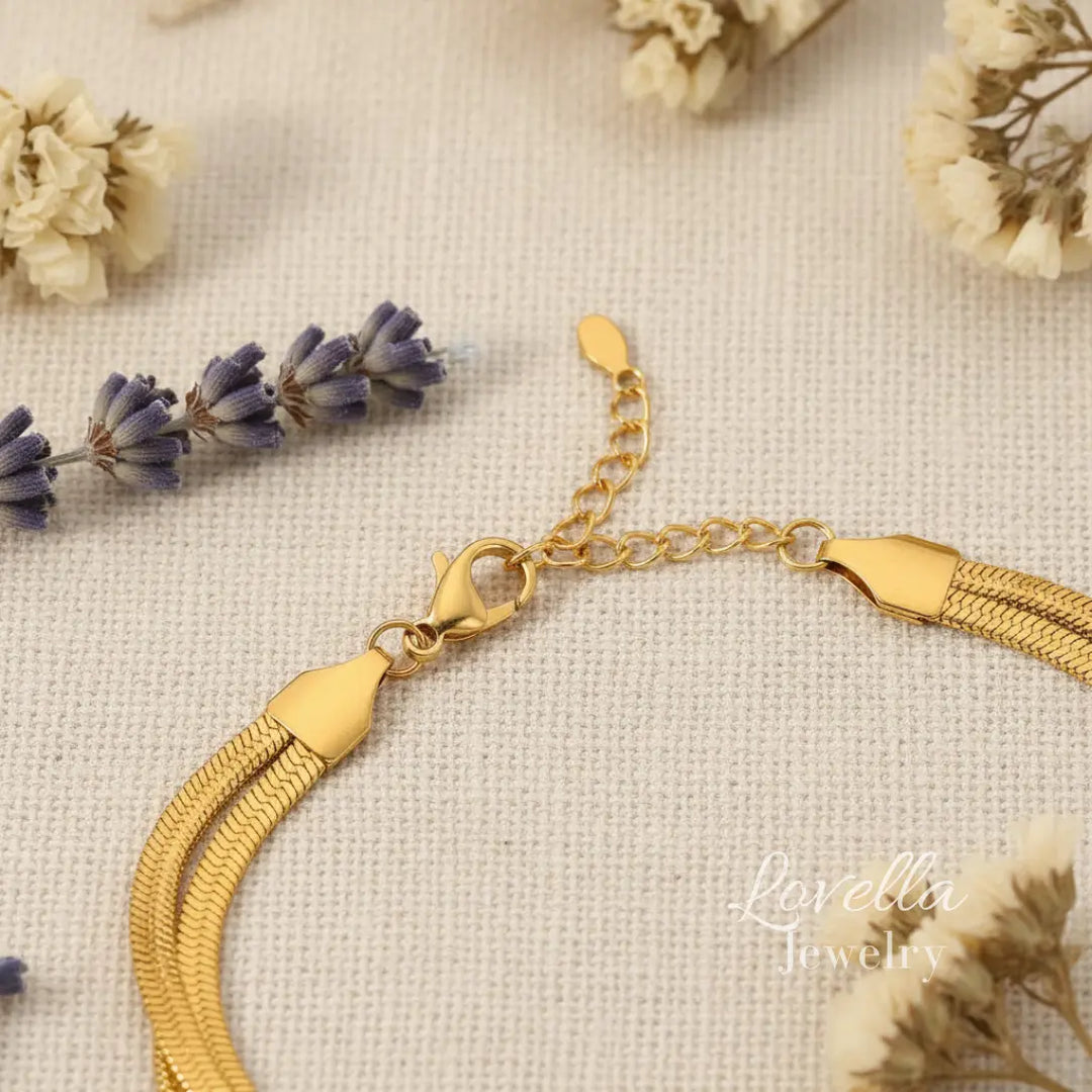 Gold bracelet with tassel on a textured surface with flowers