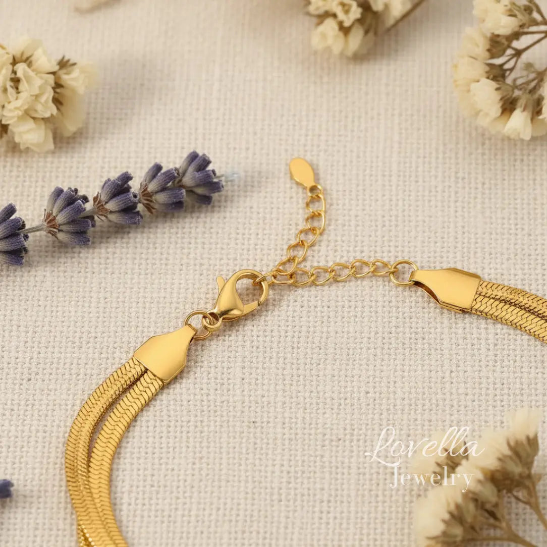 Gold bracelet with tassel on a textured surface with flowers