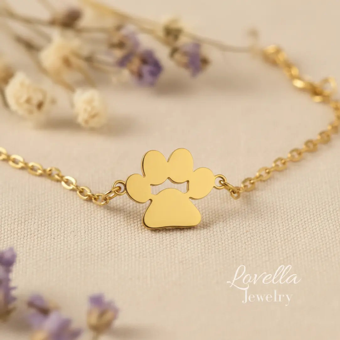 Gold paw print bracelet on a beige background with 'Lovella Jewelry' branding.