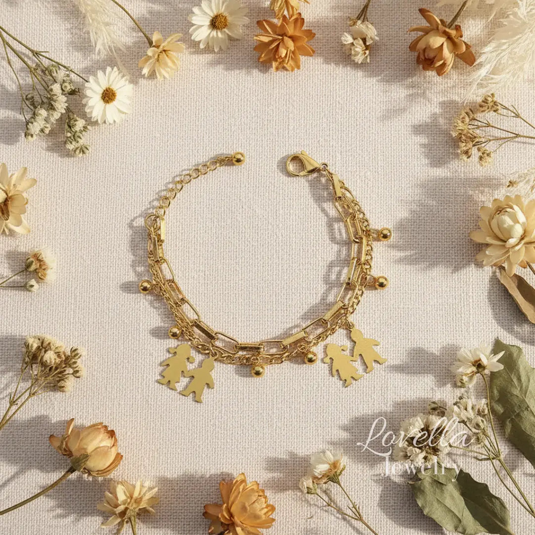 Gold bracelet with leaf charms on a background of dried flowers, featuring the brand 'Lovella Jewelry'.