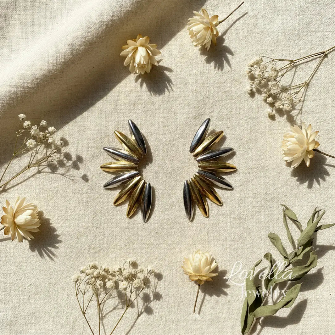 Two-tone gold and silver spike stud earrings on cream background 