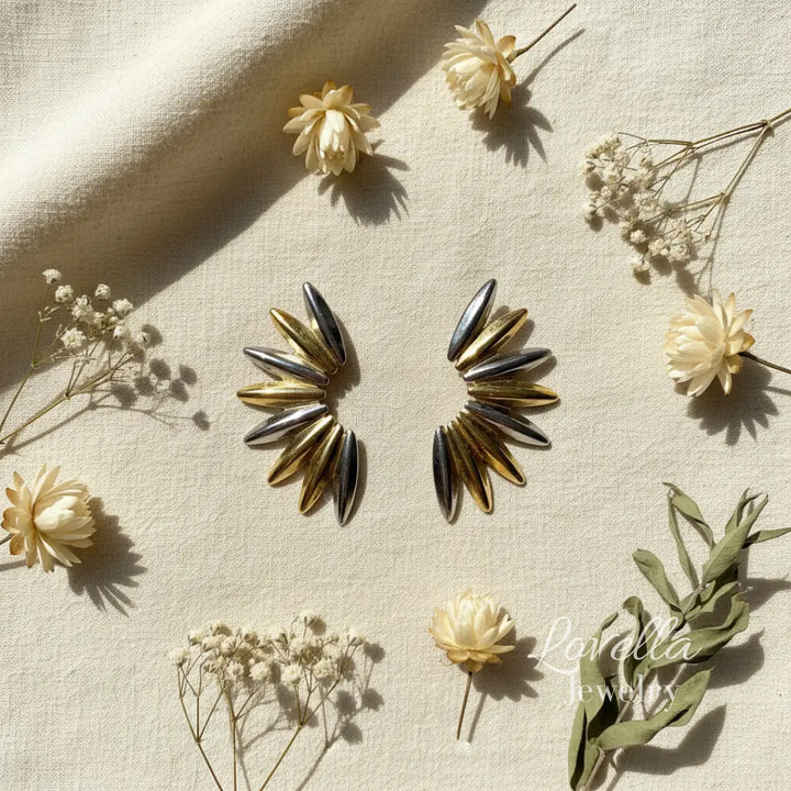 Two-tone gold and silver spike stud earrings on cream background 