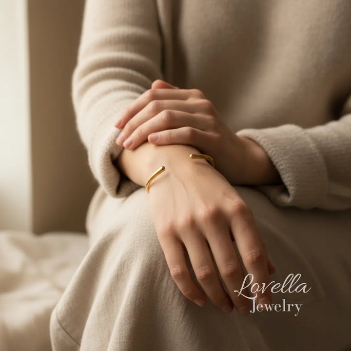 Close-up of a person's wrist wearing gold bracelets with 'Lovella Jewelry' branding.
