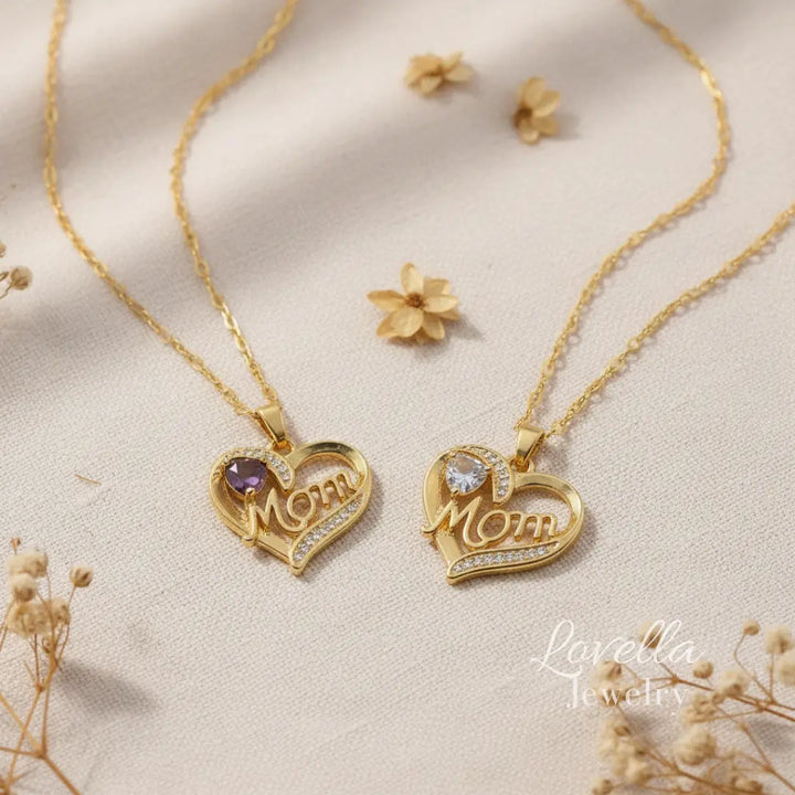 Two gold-tone stainless steel heart necklaces with "Mom" pendant, featuring zirconia stones and center stone in purple and clear options.