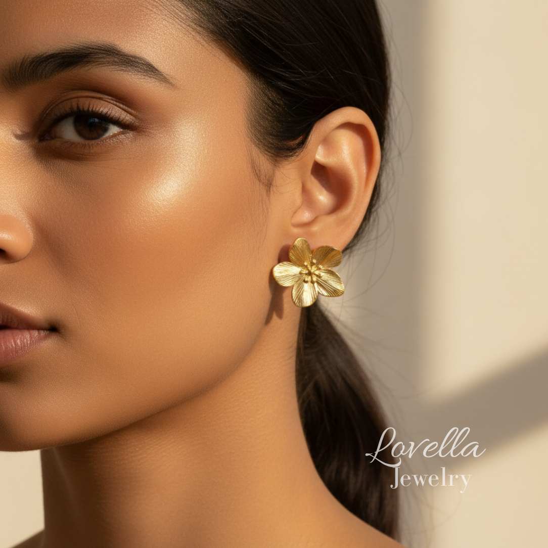 Close-up of a woman wearing gold flower earrings with 'Lovella Jewelry' branding.