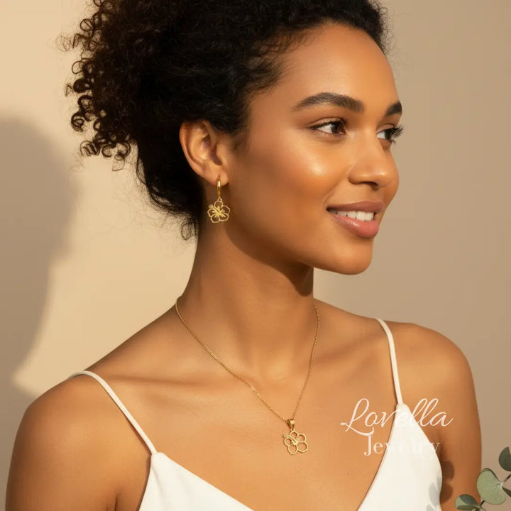 Woman wearing gold earrings and necklace with a beige background