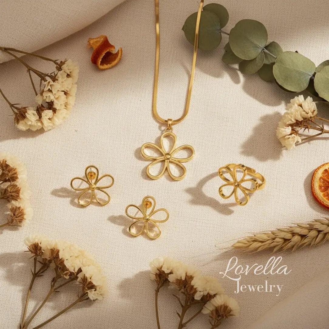 Gold floral jewelry set with necklace and earrings on a neutral background with dried flowers and leaves.
