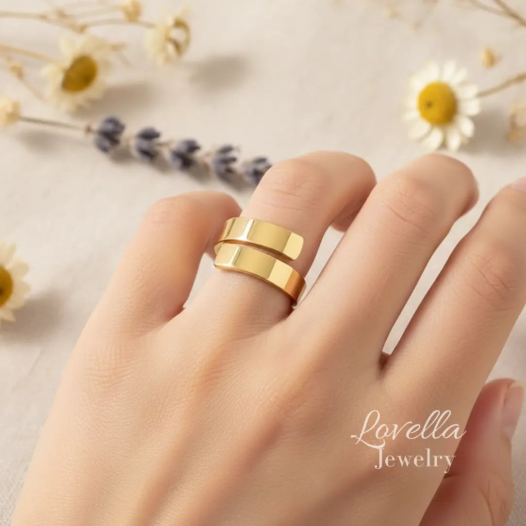 Gold ring on a finger with 'Lovella Jewelry' branding, against a soft floral background.