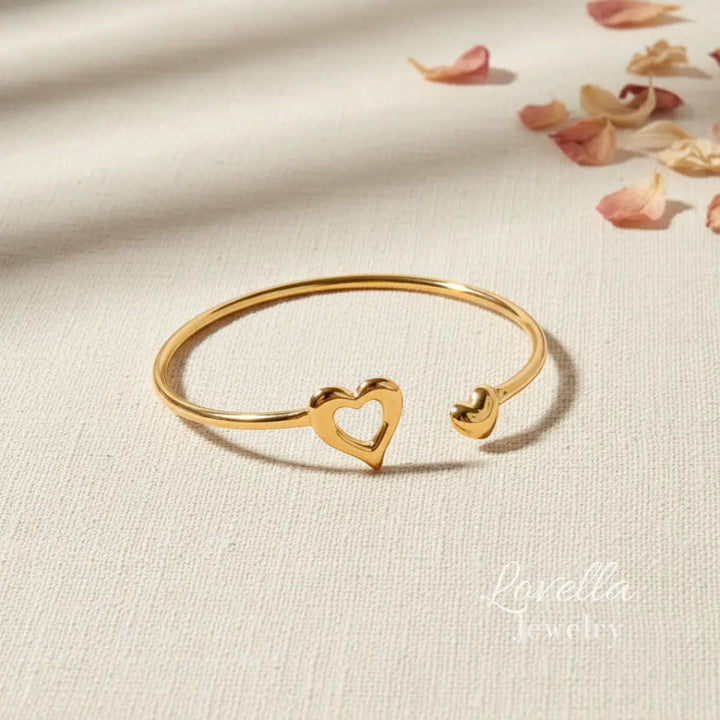 Gold bracelet with heart design on a beige fabric background