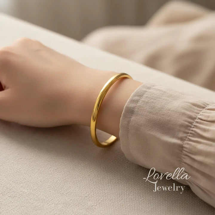 Gold bracelet on a wrist with 'Lovella Jewelry' branding.