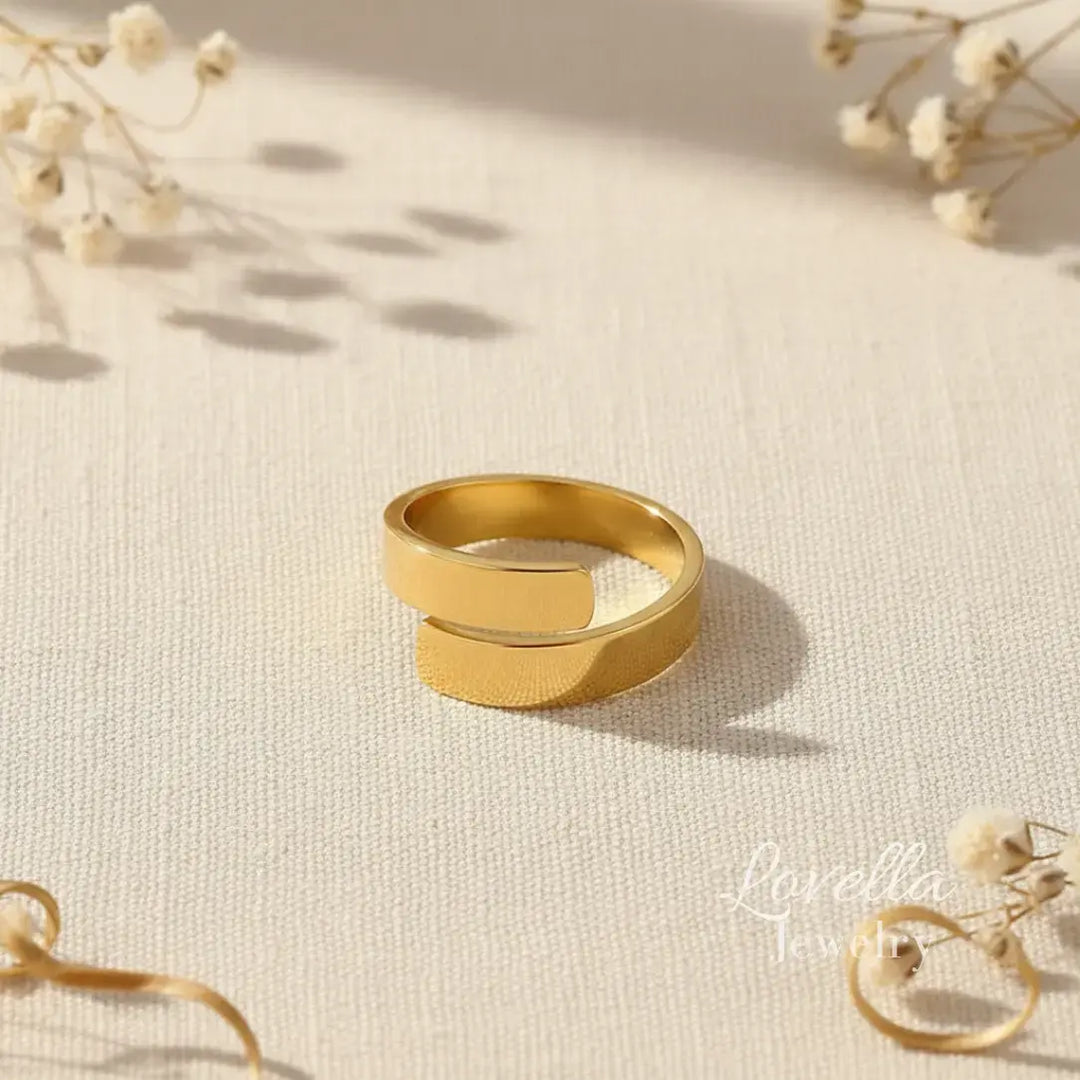 Gold ring on a textured beige surface with dried flowers