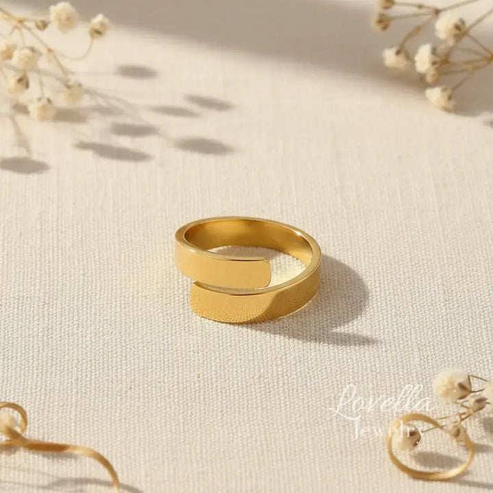 Gold ring on a textured beige surface with dried flowers