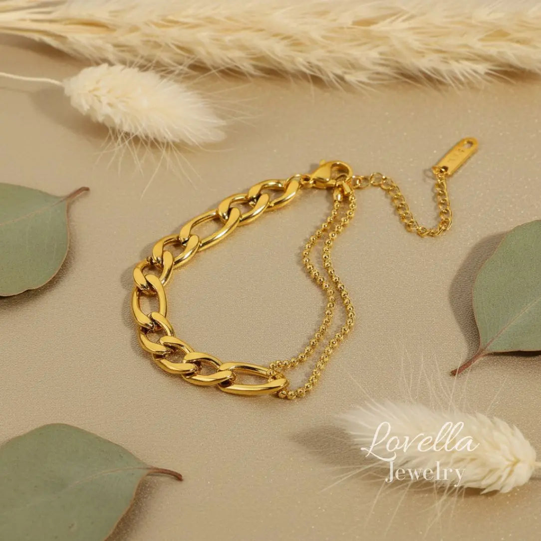 Gold chain bracelet on a neutral background with decorative elements, featuring Lovella Jewelry branding.