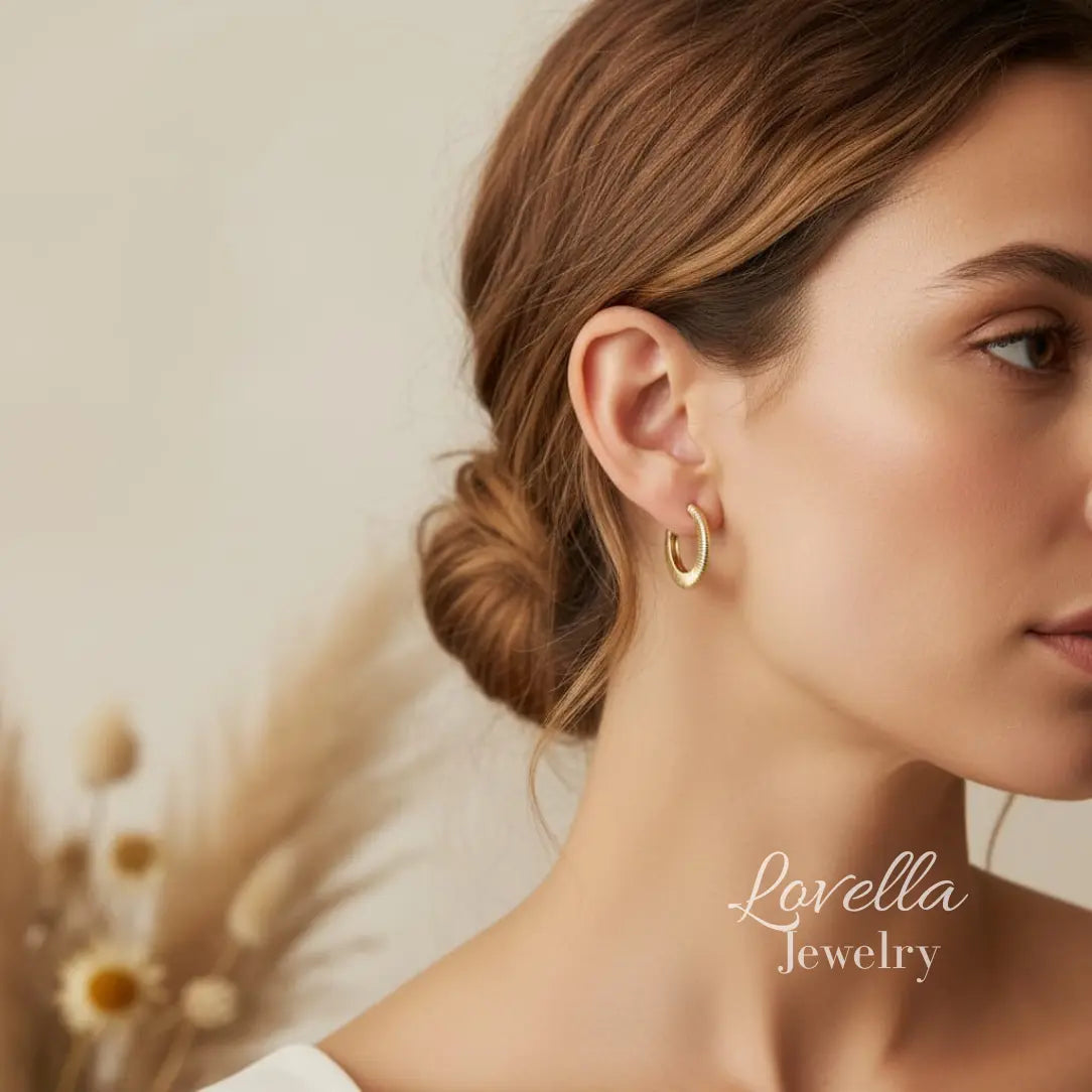 Close-up of a woman wearing gold hoop earrings with 'Lovella Jewelry' branding.