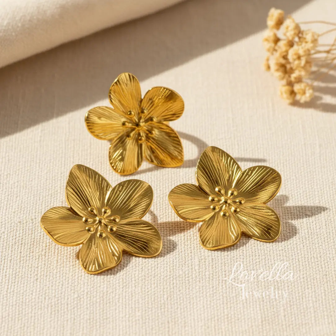 Gold floral earrings on a beige fabric background