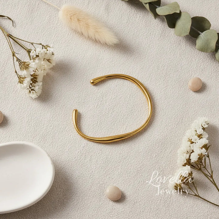 Gold bracelet on a light surface with decorative elements and 'Lovelisa Jewelry' branding.