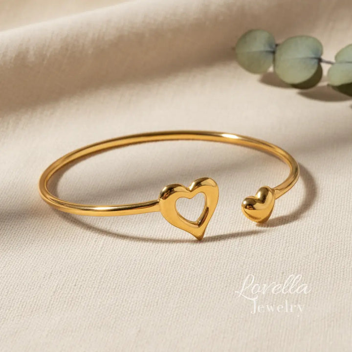 Gold heart-shaped bracelet on a beige fabric background with 'Lorella Jewelry' branding.