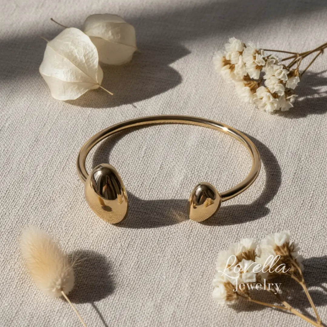 Gold bracelet on a light surface with dried flowers
