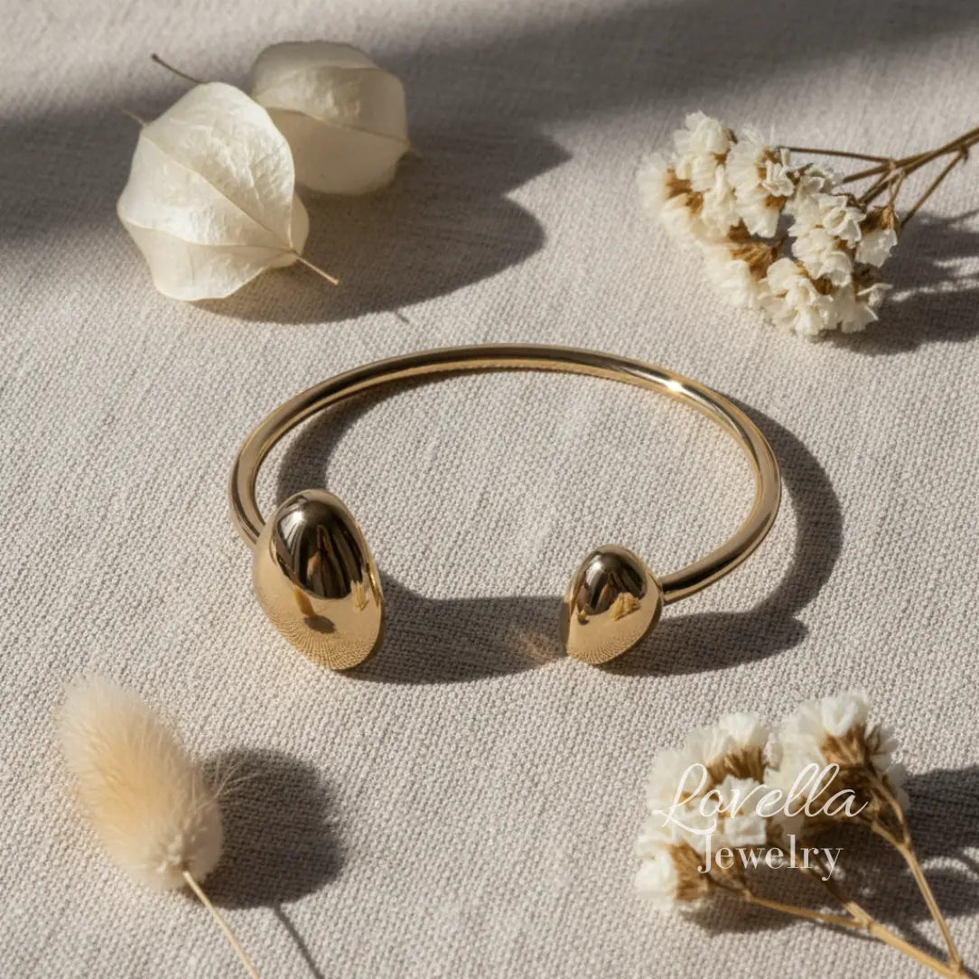 Gold bracelet on a light surface with dried flowers