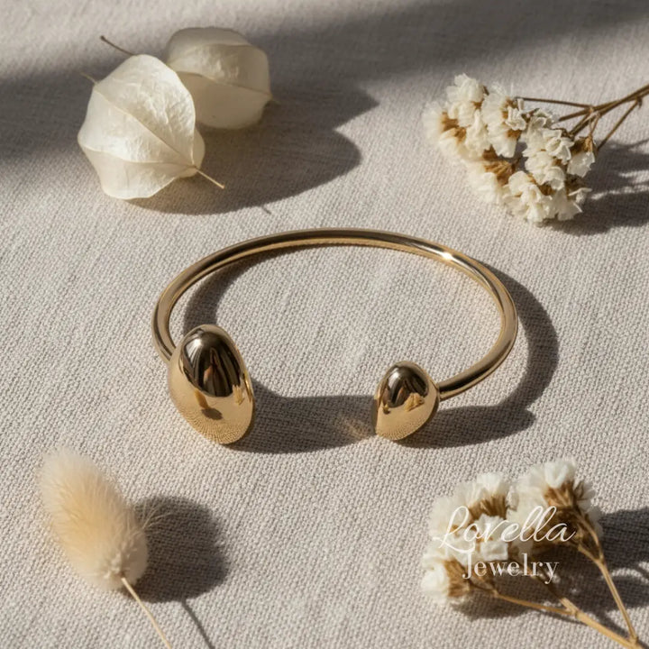 Gold bracelet on a light surface with dried flowers