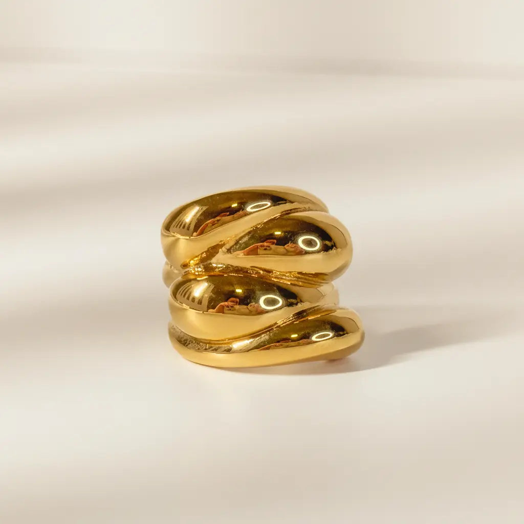 Gold ring with a textured design on a beige background