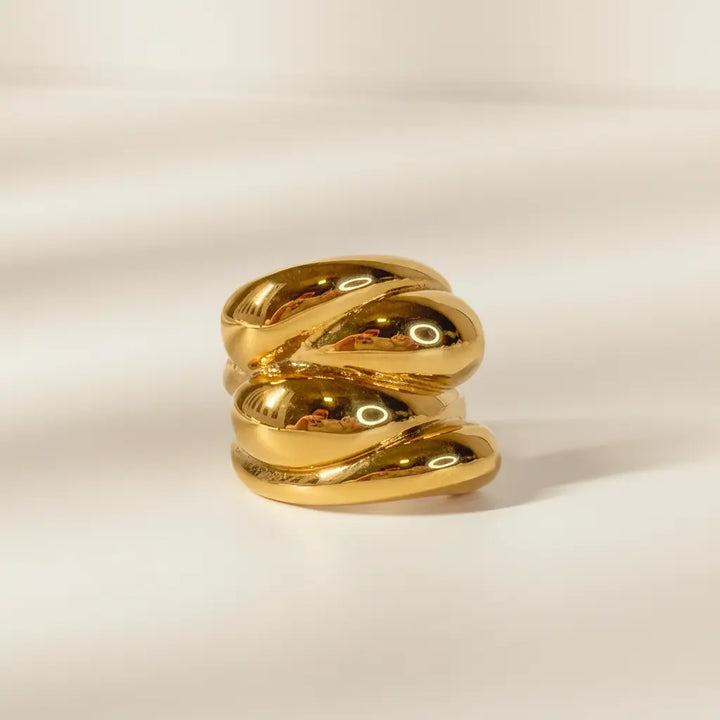 Gold ring with a textured design on a beige background