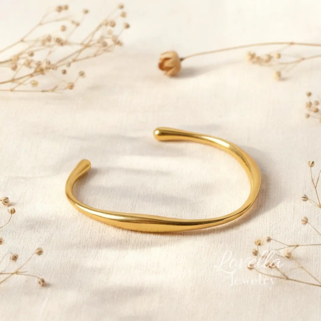 Gold bracelet on a light fabric background with dried flowers