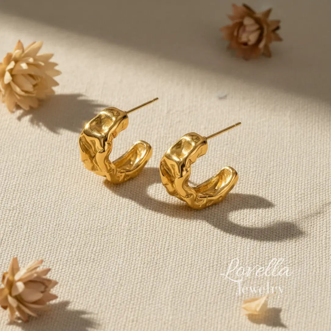 Gold hoop earrings on a beige surface with 'Lovella Jewelry ' branding.