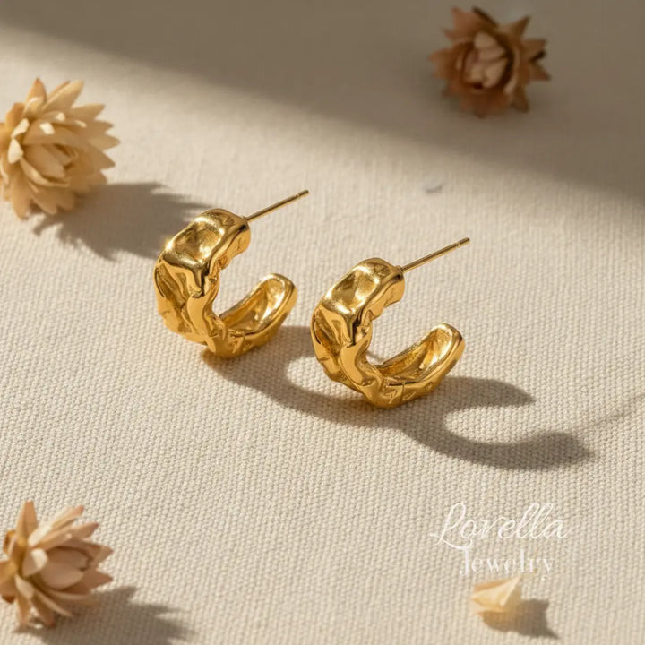 Gold hoop earrings on a beige surface with 'Lovella Jewelry ' branding.