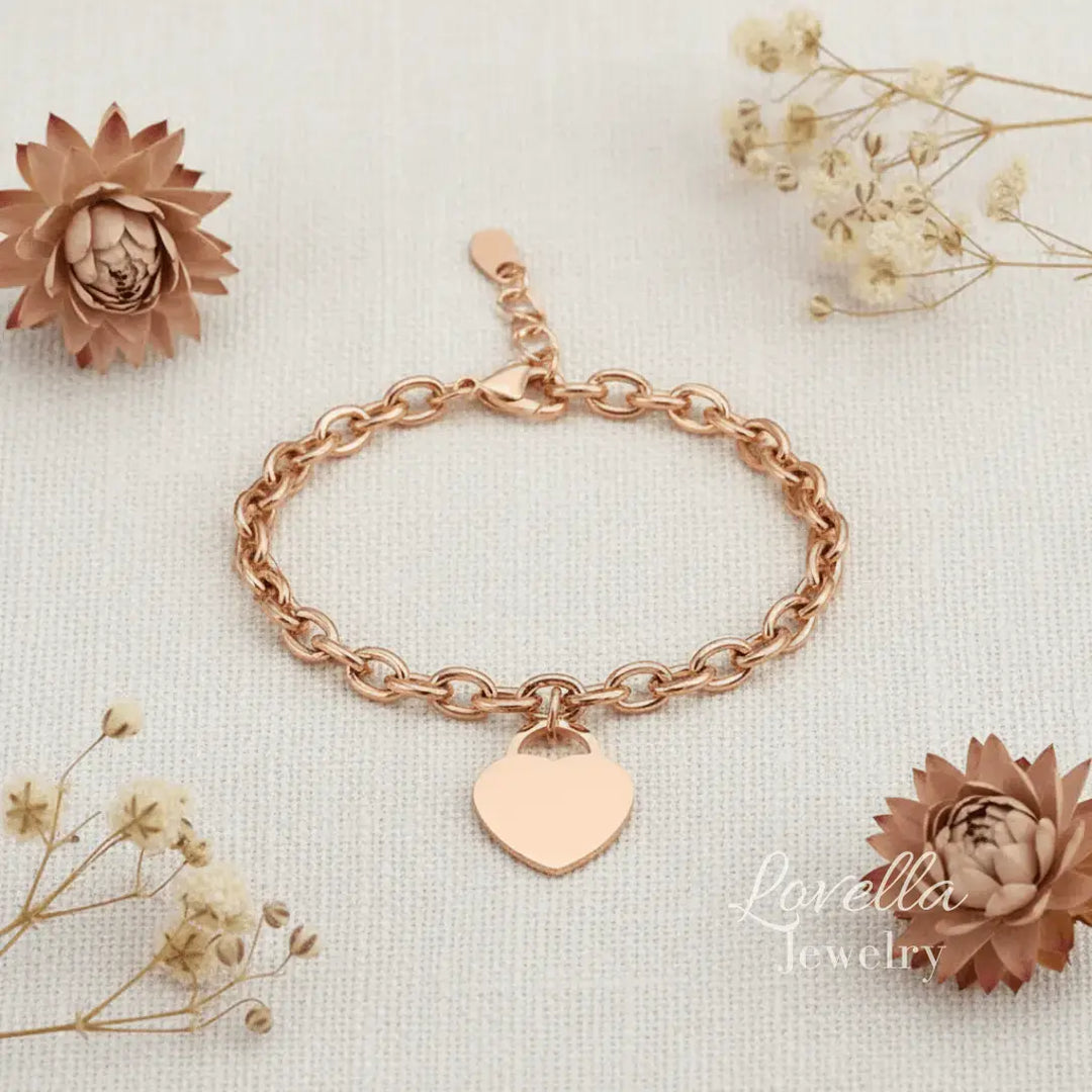 Rose gold bracelet with a heart charm on a light background with decorative flowers.